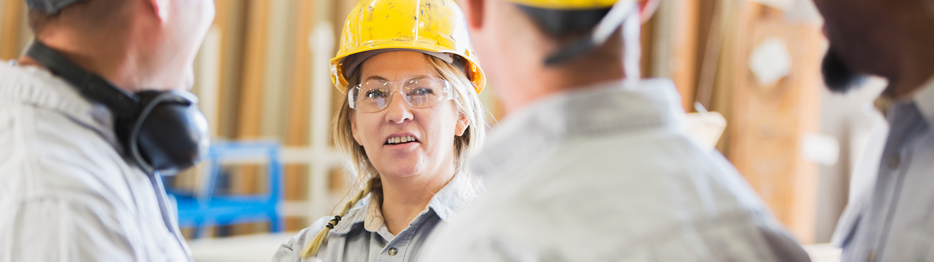 Female worker with hard hat speaking to others