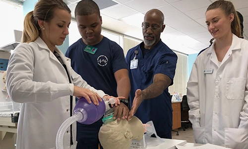 A group of medical students practicing on a medical dummy