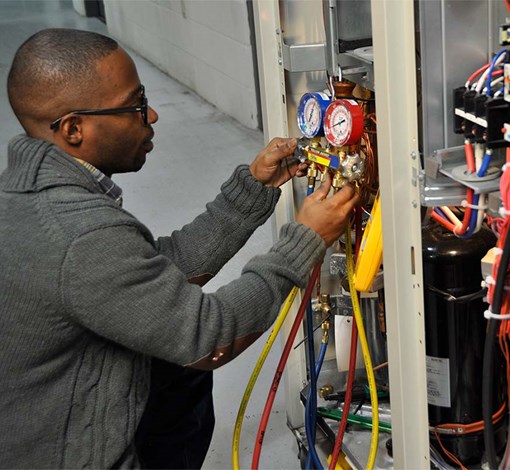 A man using A/C gauges on an air conditioning unit