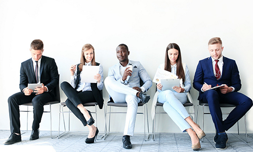 A group of people in business attire waiting in chairs