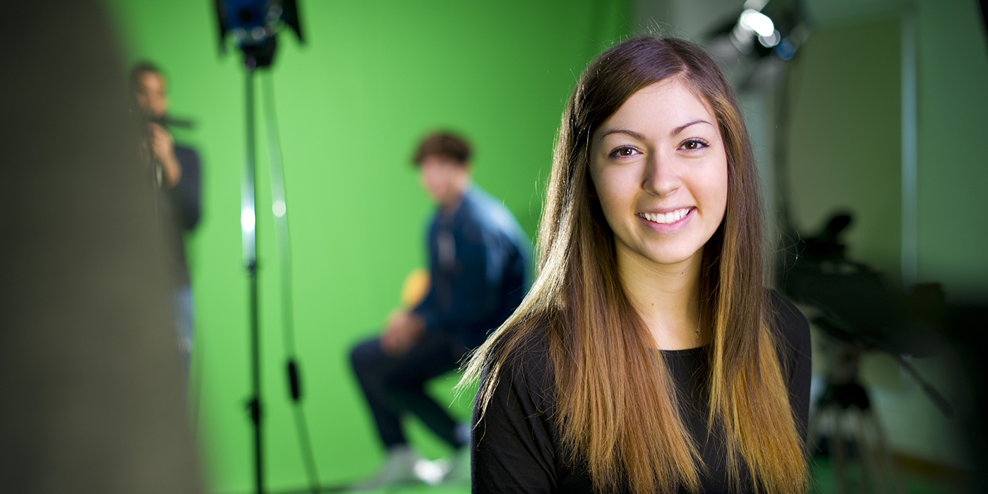 A smiling woman in front of a green screen