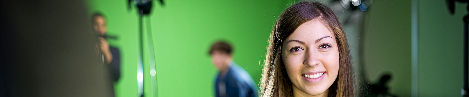 A smiling woman in front of a green screen
