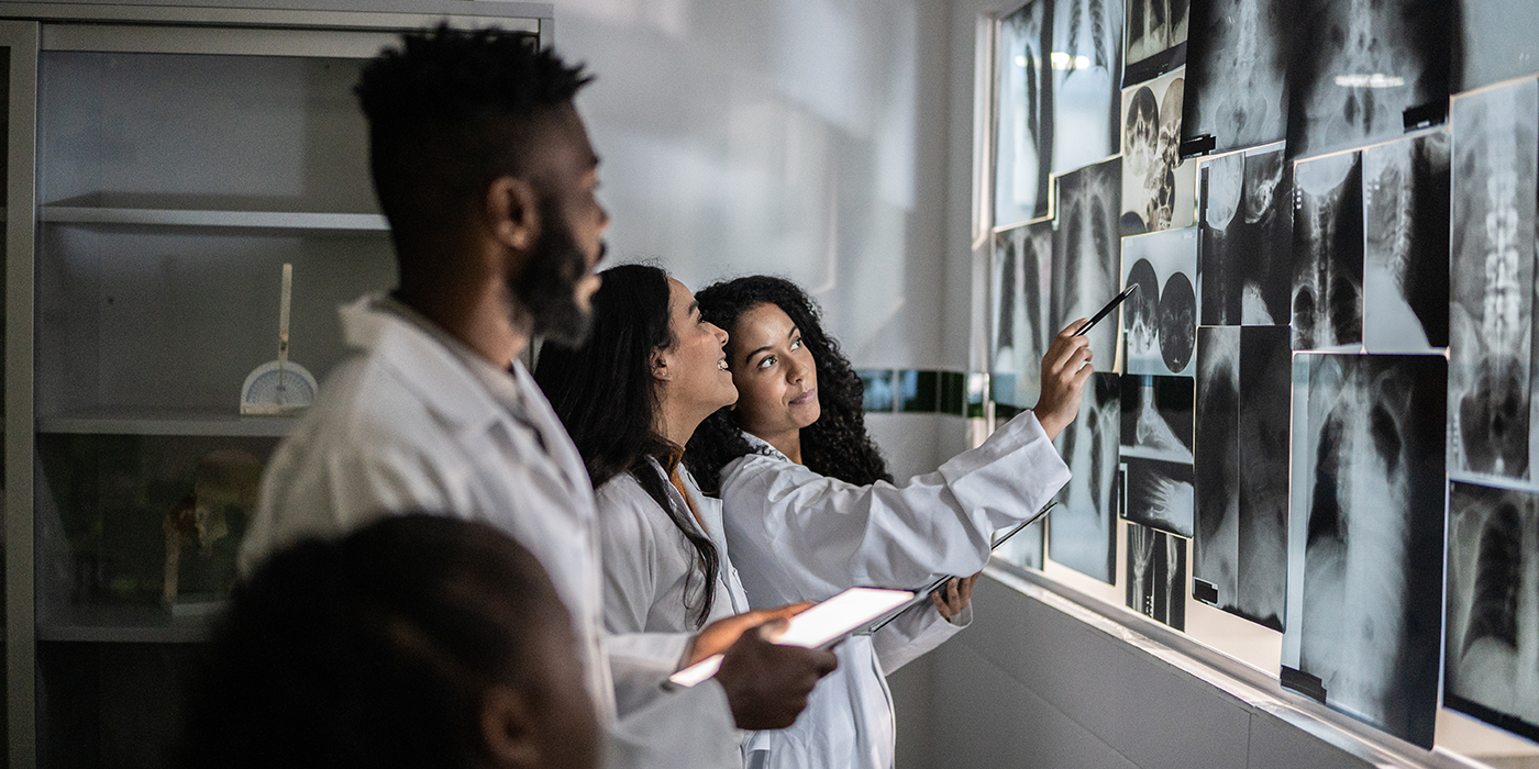 3 medical professionals analyzing x-rays