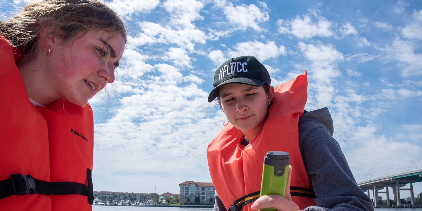 Two people on a boat doing analysis