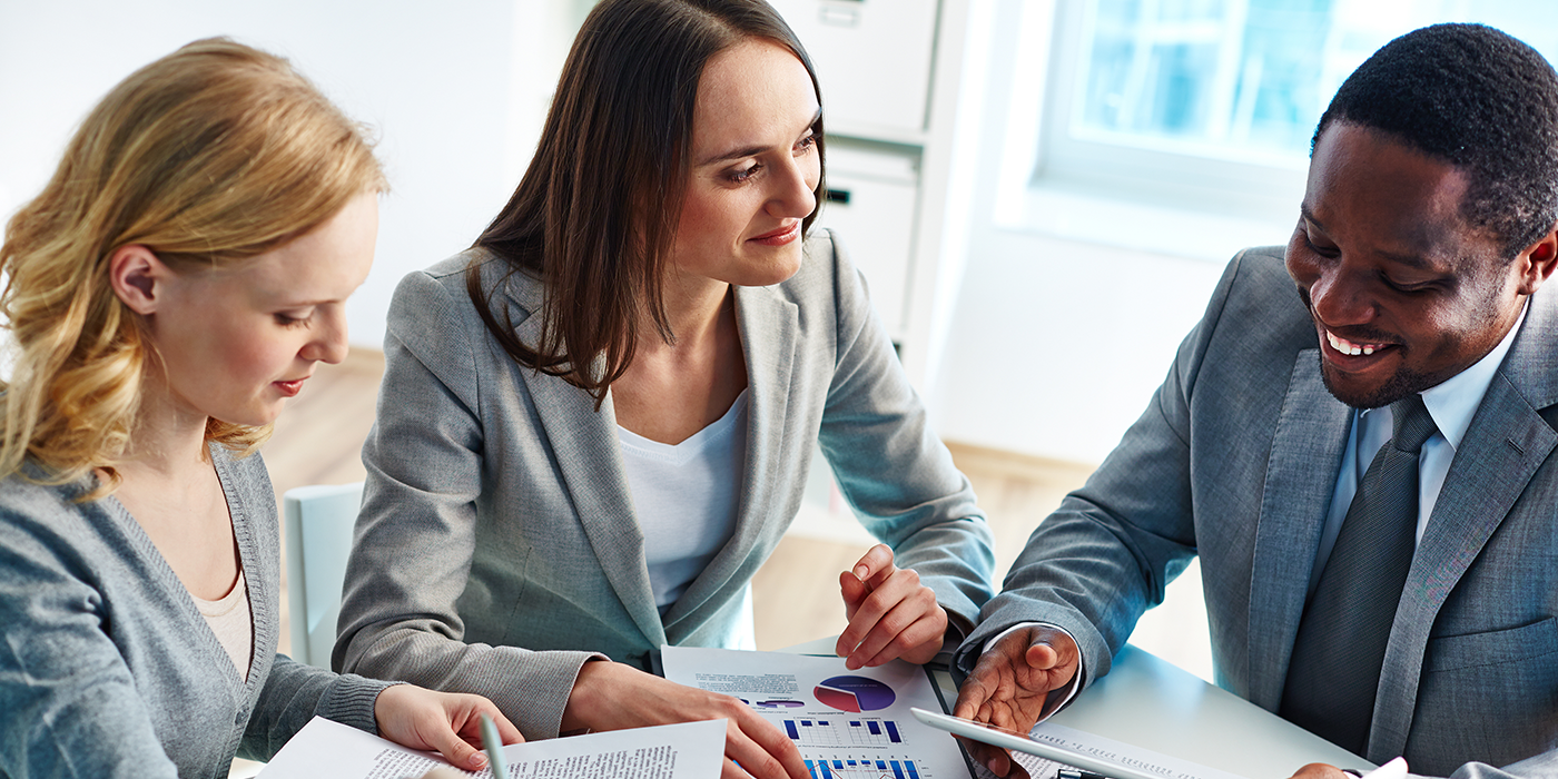 Three people analyzing charts