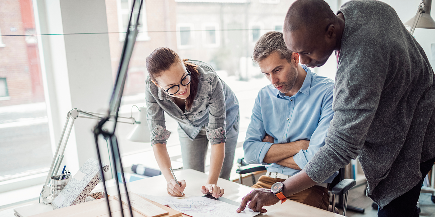 Multiple people analyzing papers in an office