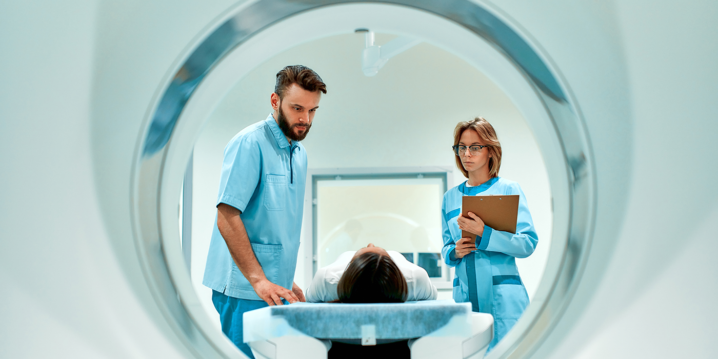 People in medical attire putting a person into an MRI machine