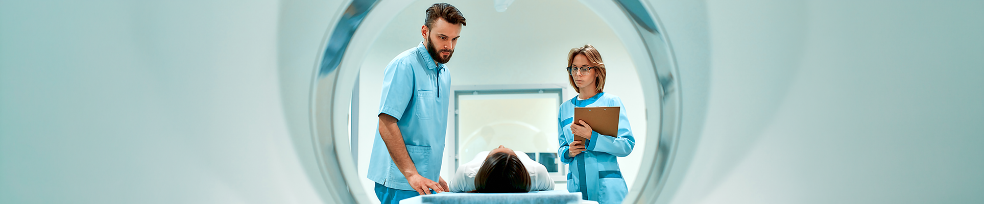 People in medical attire putting a person into an MRI machine
