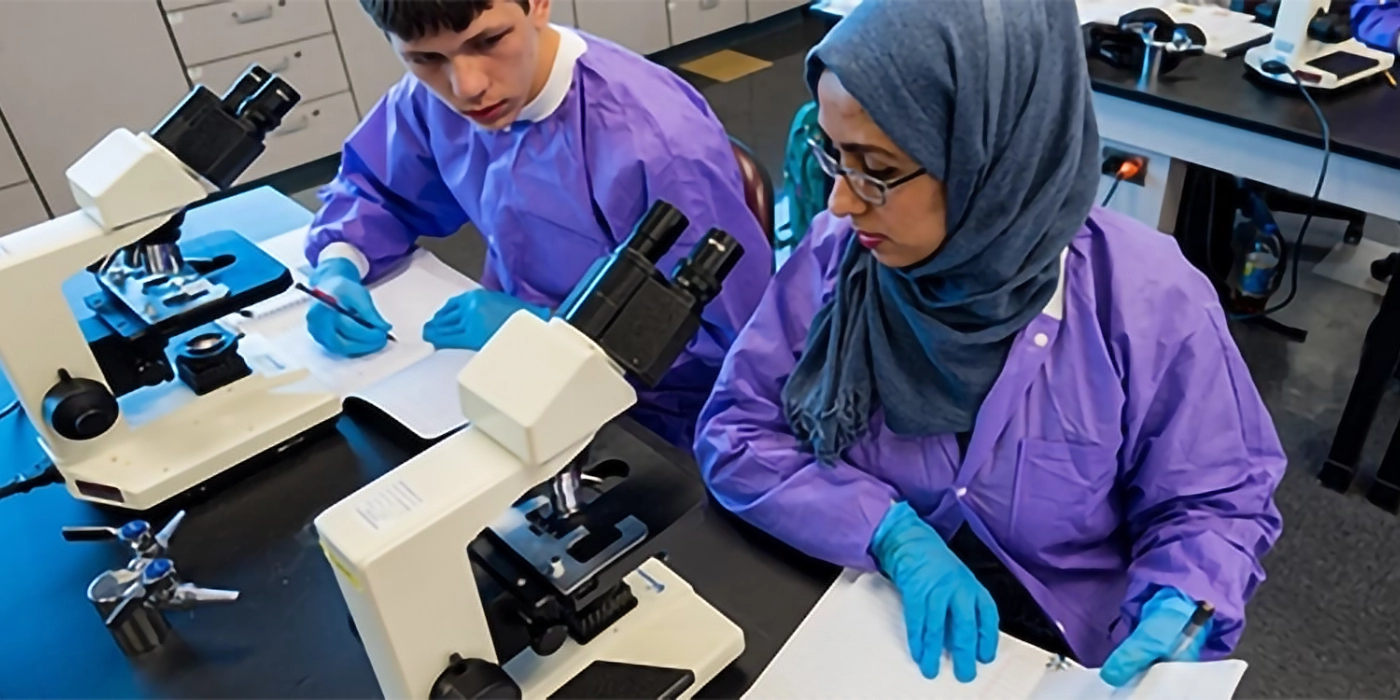 People in medical protective gear using microscopes