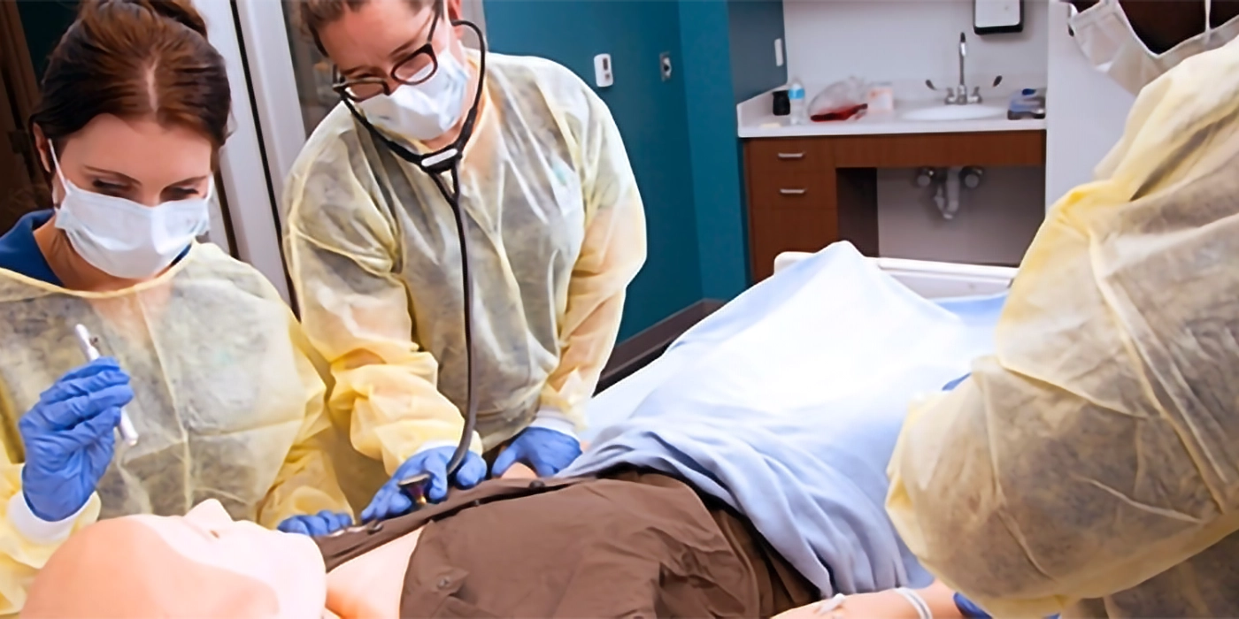 People in medical attire working on a medical practice dummy.