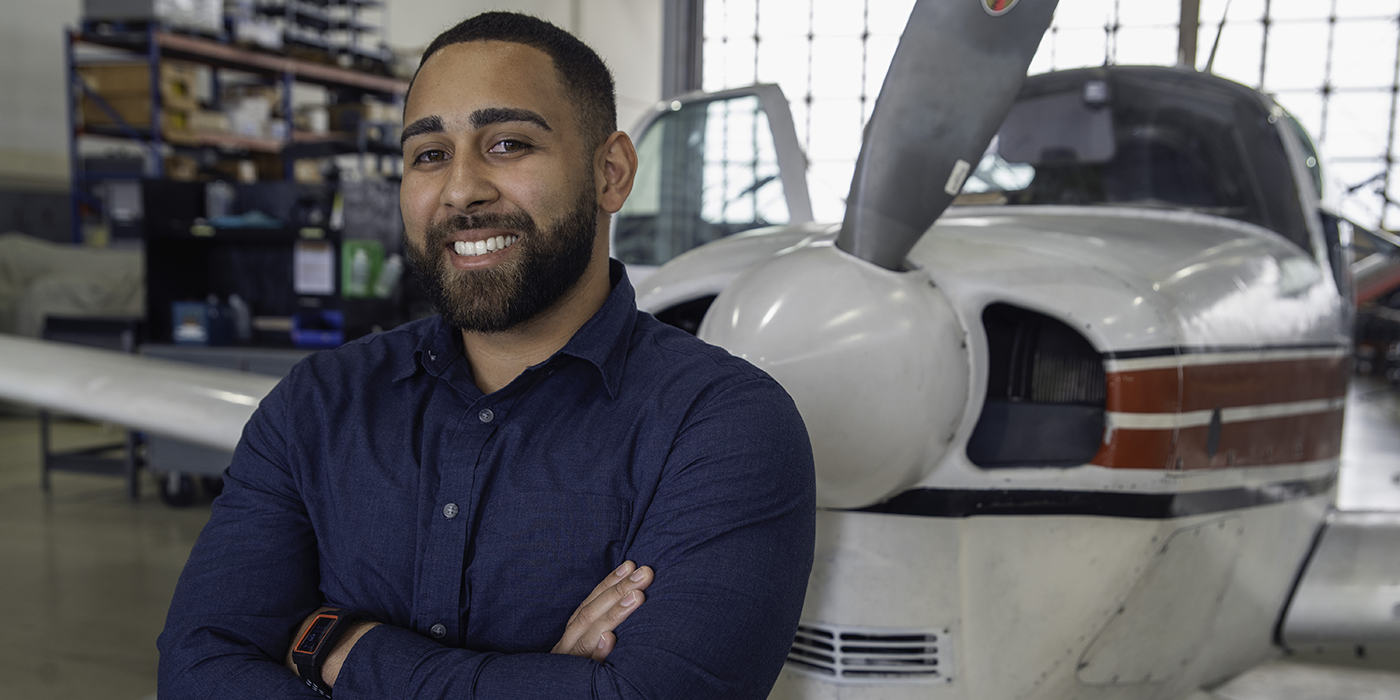 A man smiling in front of a light propeller plane