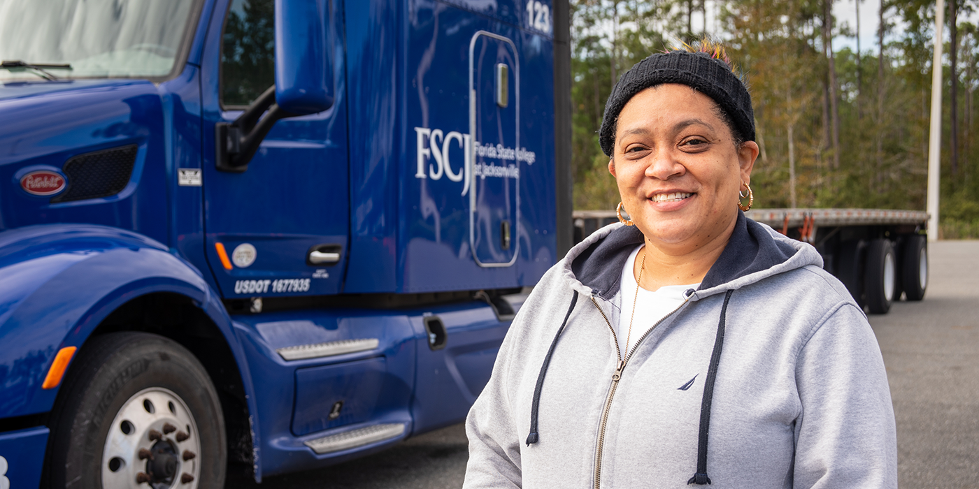 A woman in front of a semi truck