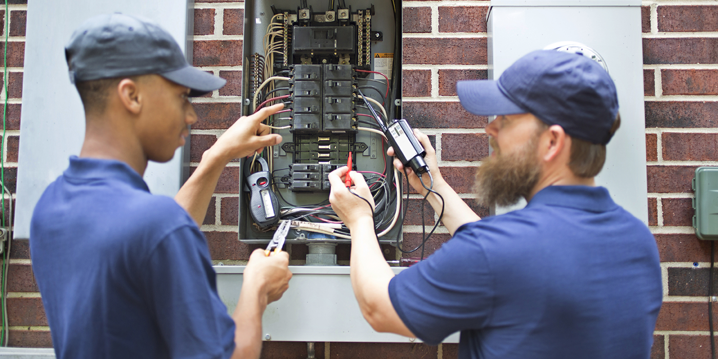 Two electricians working on an open circuit breaker panel