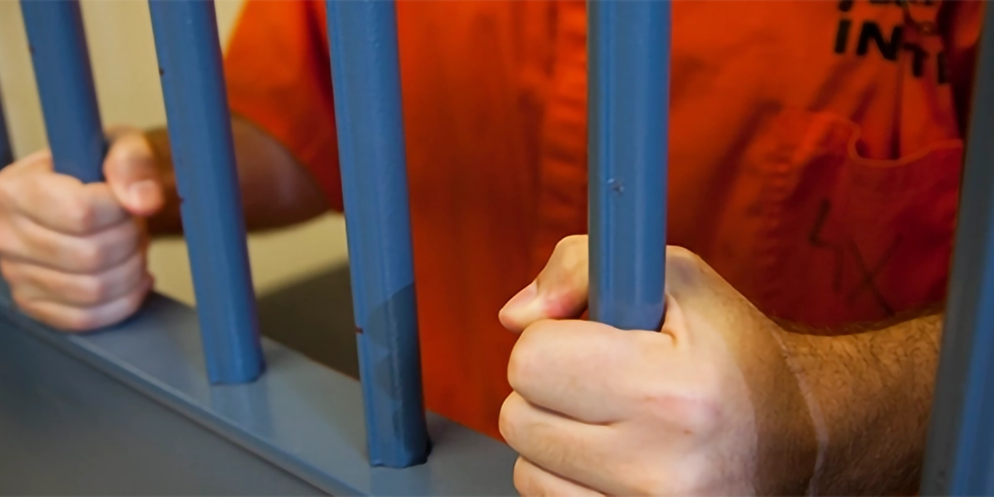 An inmate holding jail cell bars