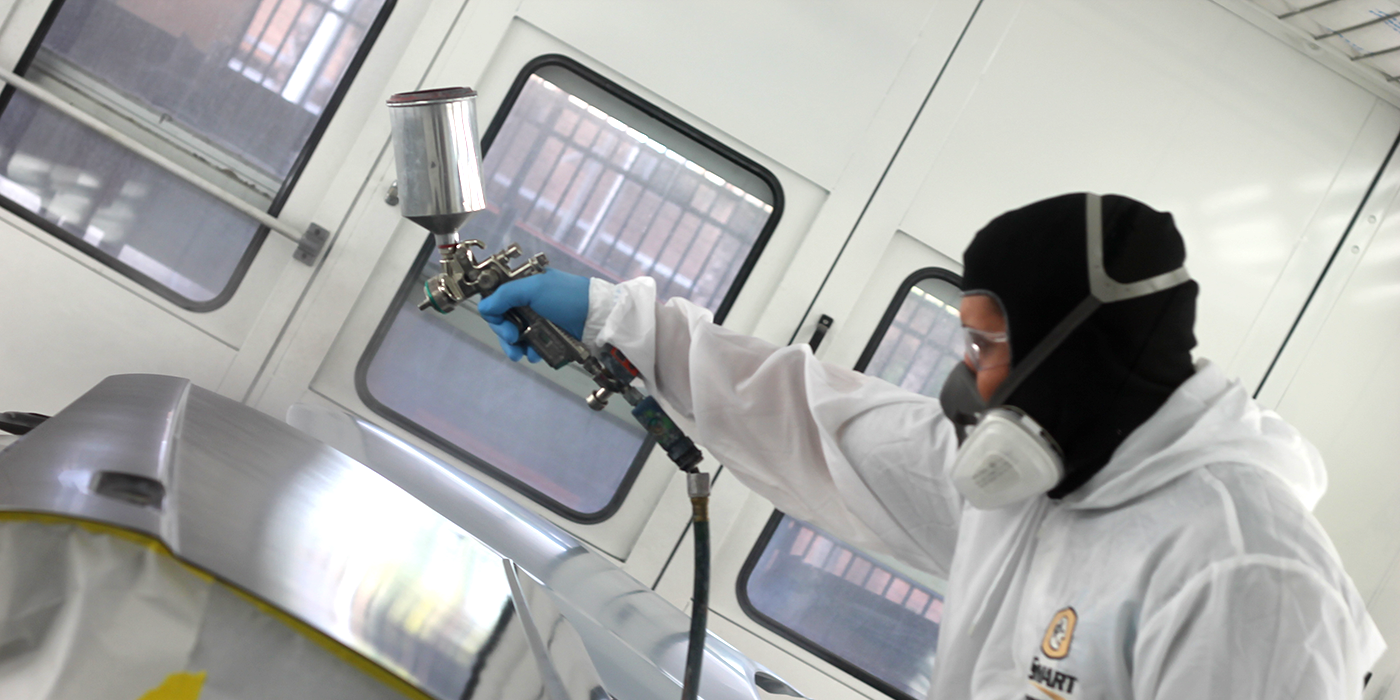 A person painting in an automotive paint booth