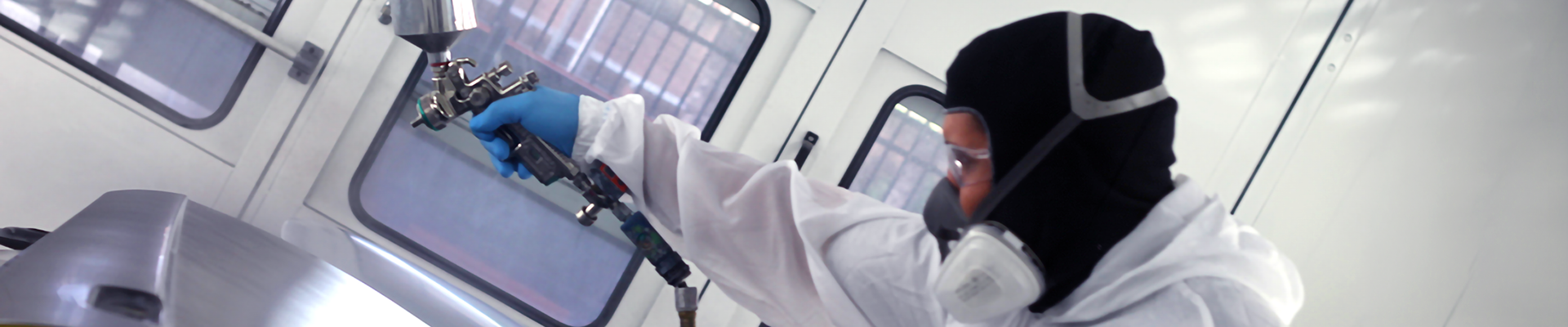 A person painting in an automotive paint booth