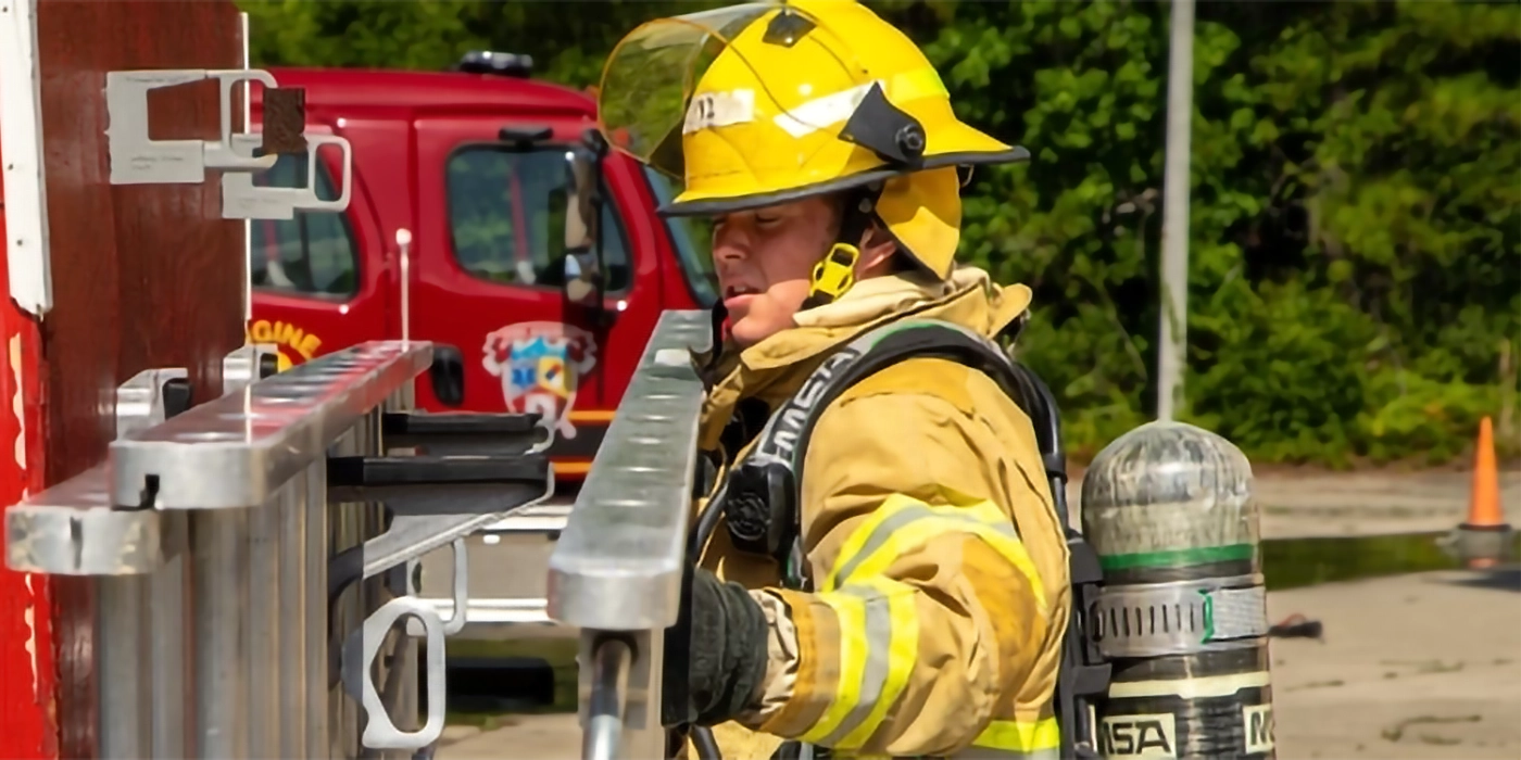 A firefighter removing a ladder from a fire truck