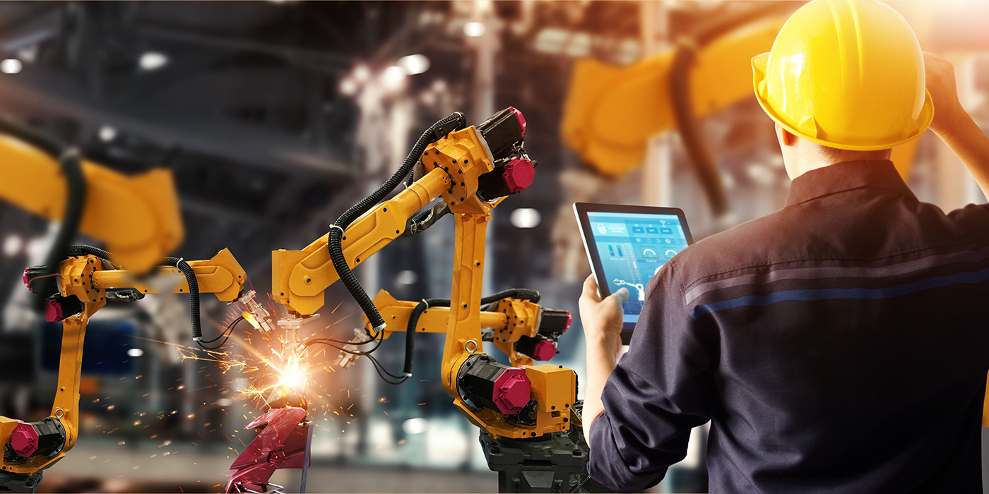 A person with a tablet in front of industrial robots