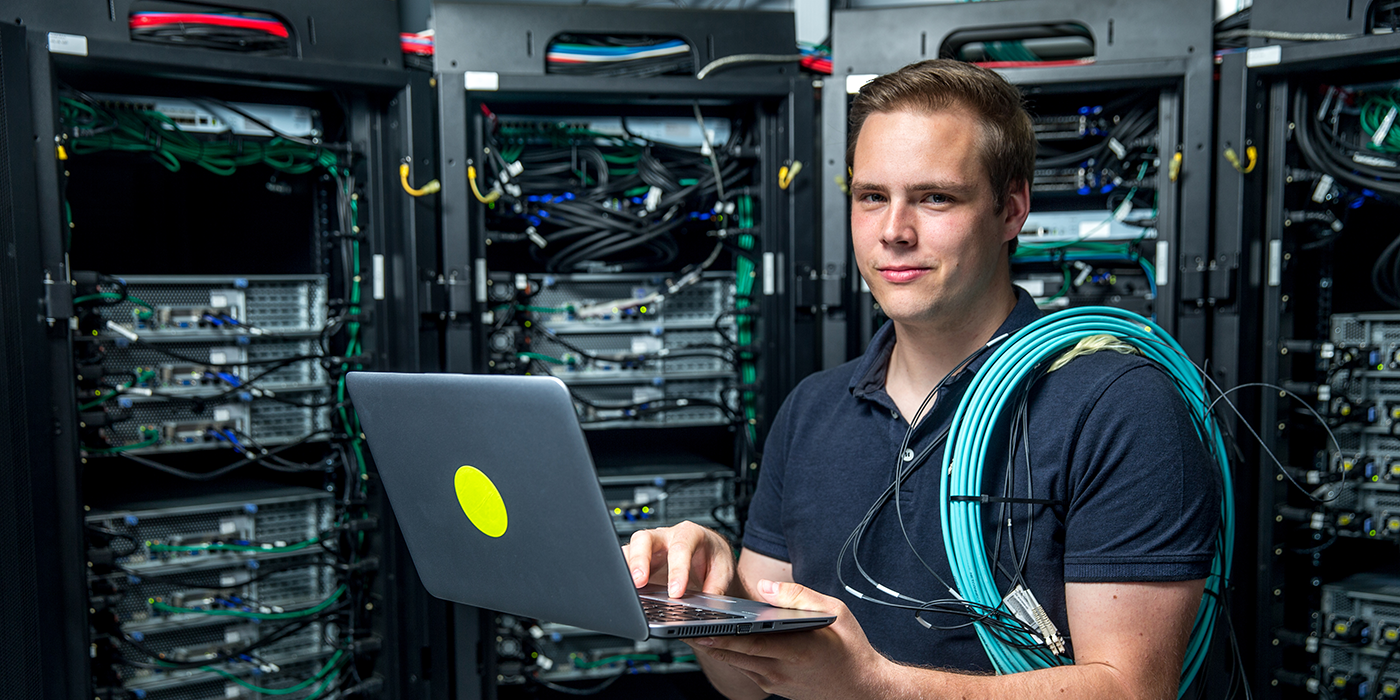 A man with ethernet cables in a network server room