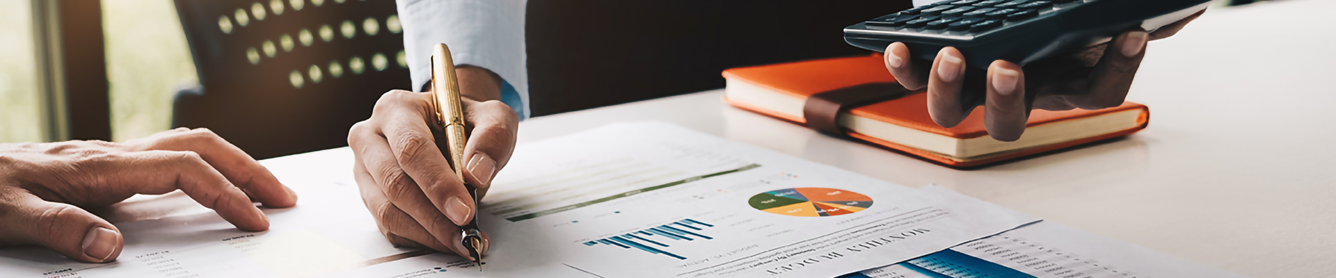 Closeup of a hand writing on a series of printed charts