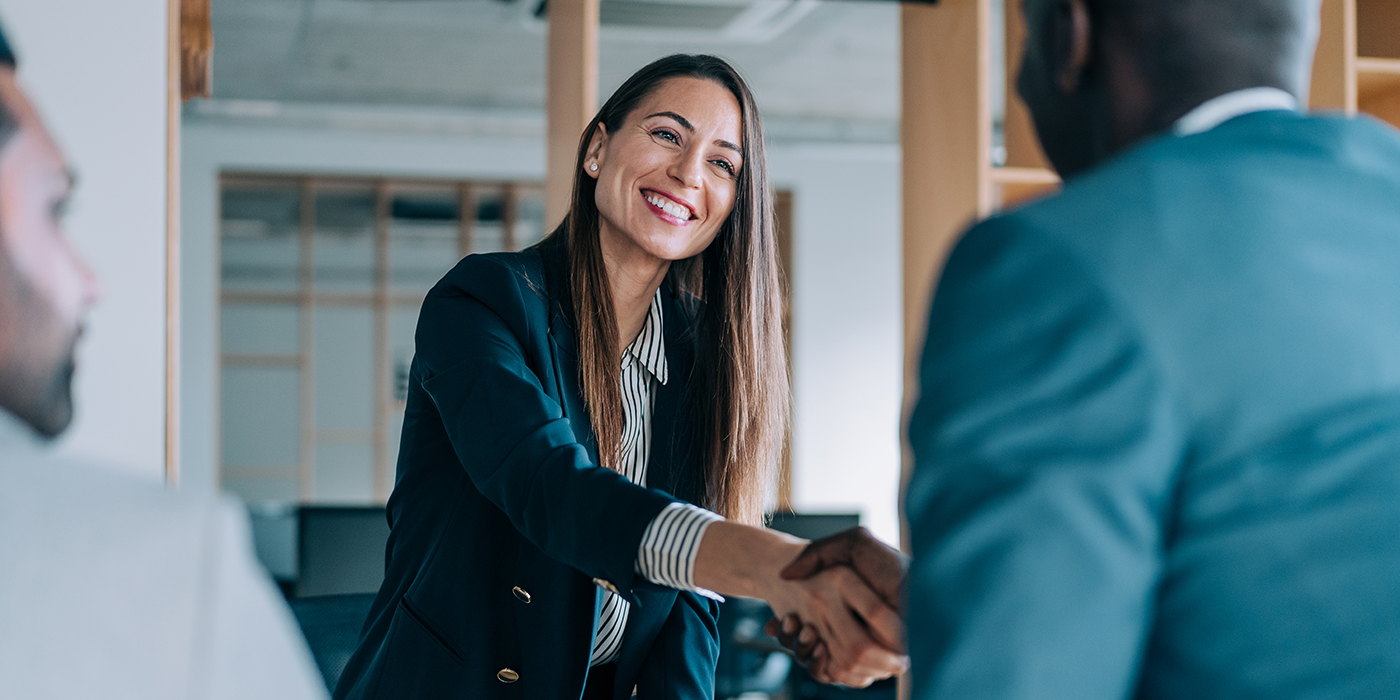 A woman and a man shaking hands in an office setting