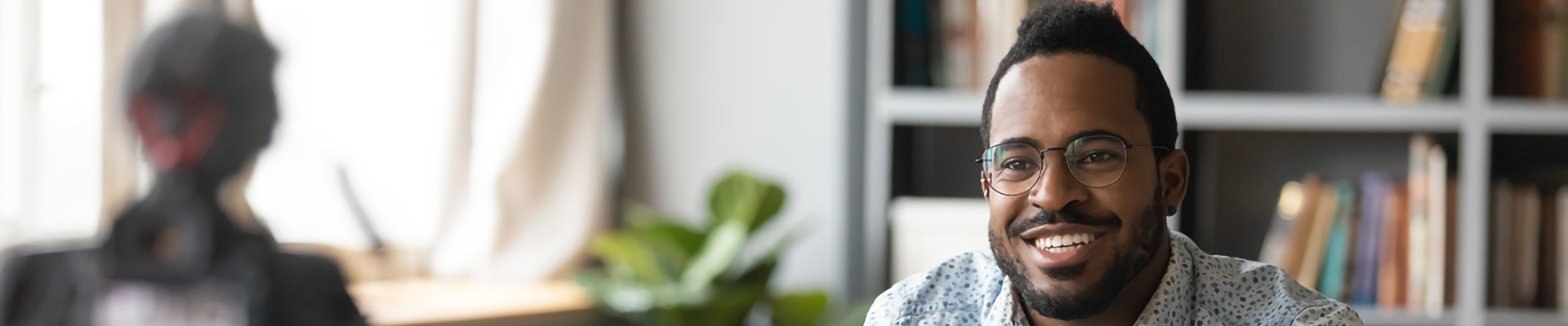 A man on a couch recording a video from a camera on a tripod