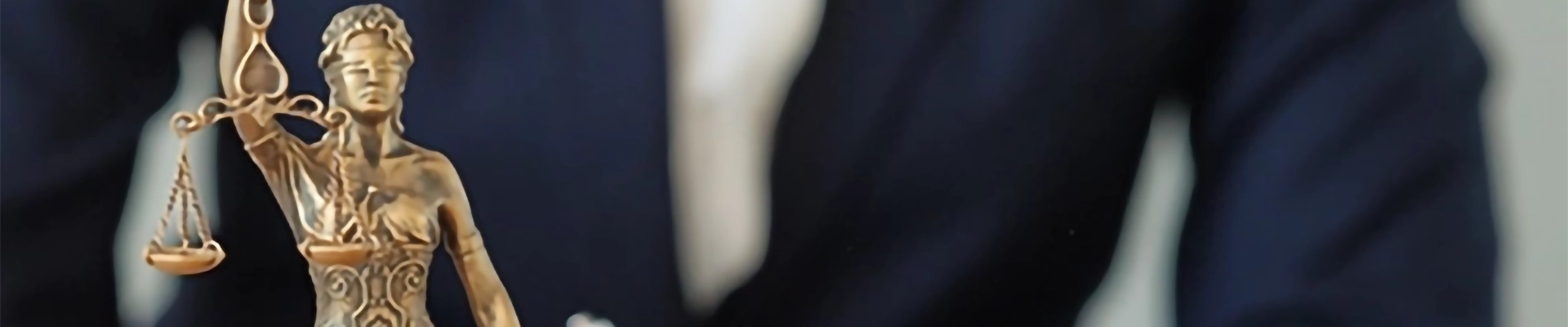 A small statue of the blind scales of justice on a desk in front of a person