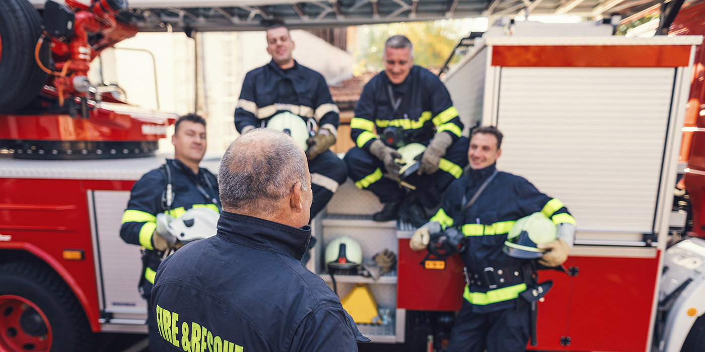 Several firefighters conversing in front of a fire truck