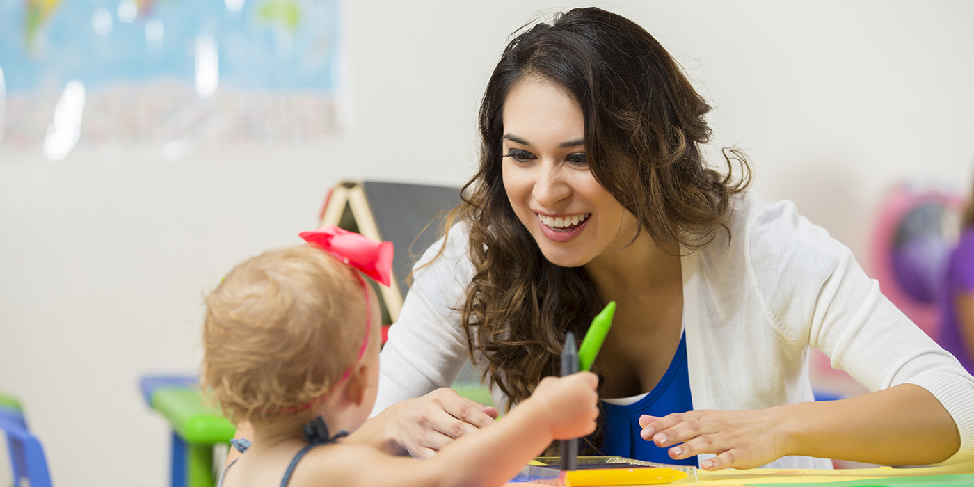 A woman interacting with a young child in an educational setting