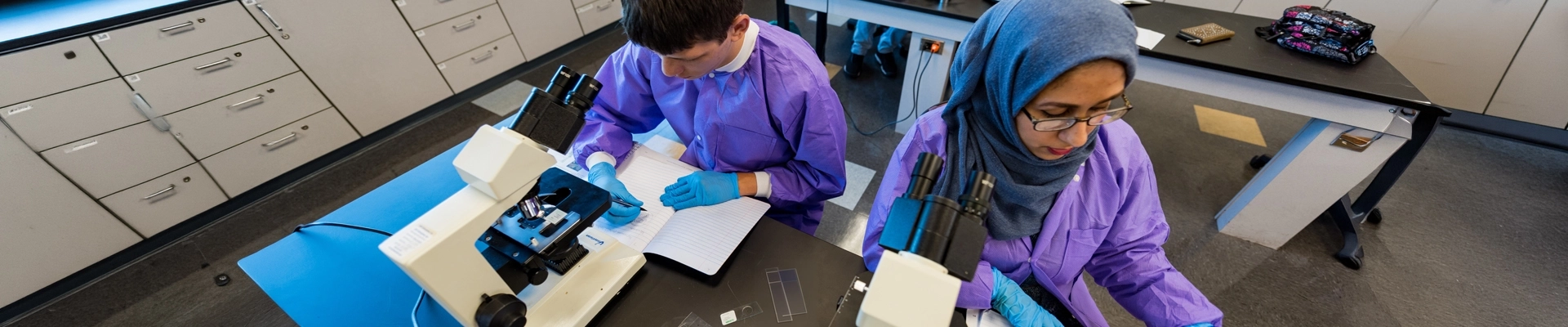 People in medical protective gear using microscopes