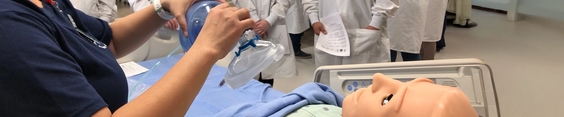 People in medical attire working on a medical practice dummy.