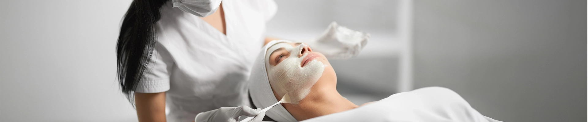 A woman applying a facial mask to another woman