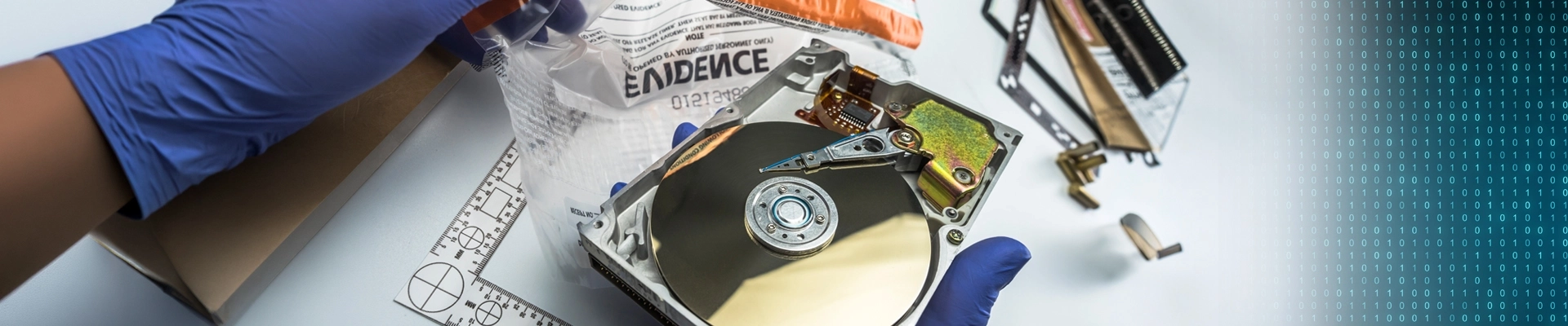 An opened up computer hard drive being put into an evidence bag