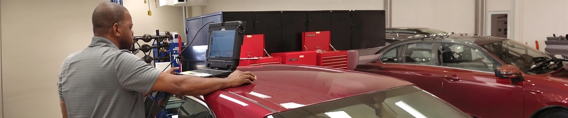 A man using a diagnostic computer on the top of a car