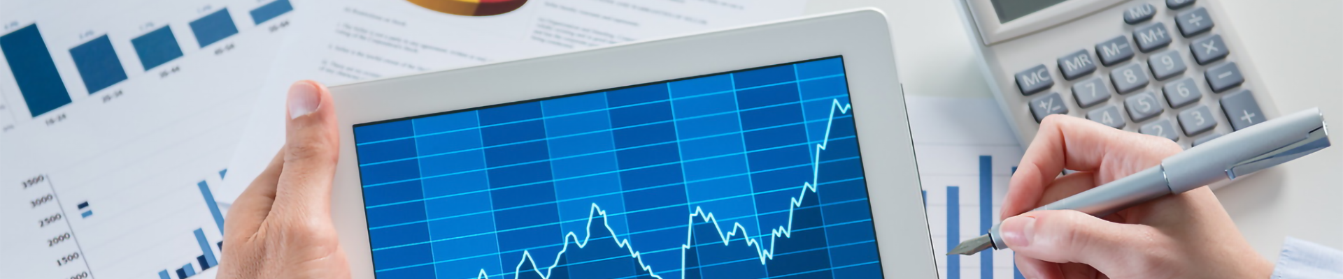 A person using a tablet with graphical overlays of finance symbols