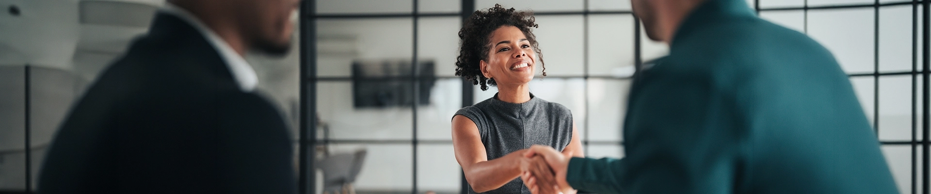 A woman and a man shaking hands in an office setting