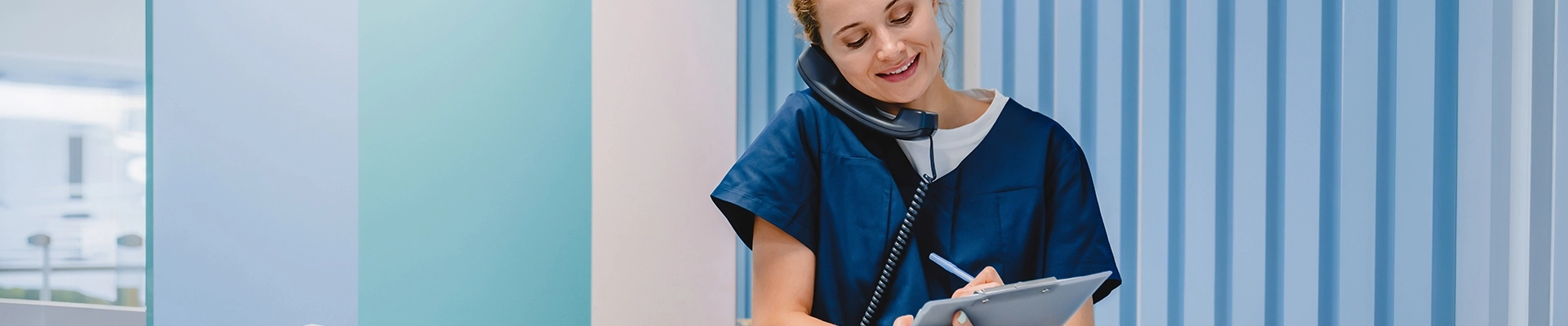 A woman in medical scrubs talking on the phone.