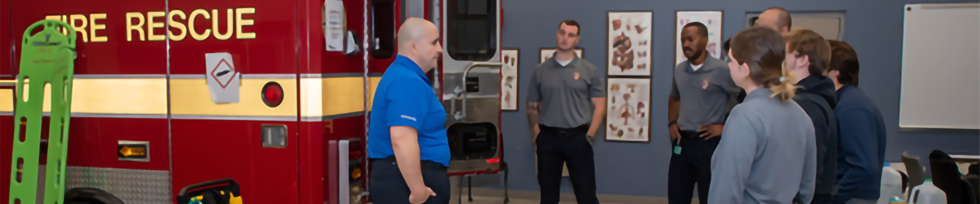 Paramedic students standing around an ambulance training mockup