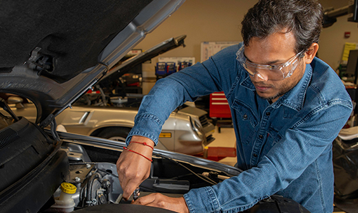 Man under hood working on car engine