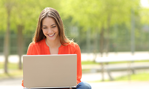 Women bat table behind laptop that is open.